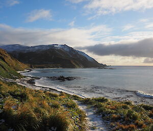 View of hill in background and snowy beach in foreground