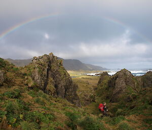 Hiker walking towards a rainbow in the distance