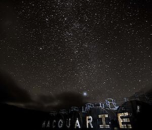 The Macquarie Island fuel farm tanks with words "macquarie Island" painted on, with starry sky overhead