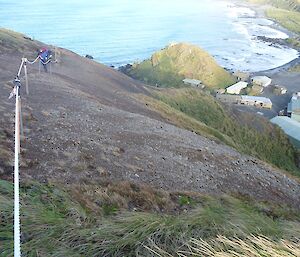 Man working onsteep slope with station in background below