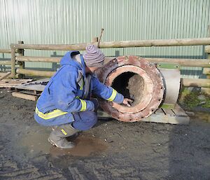 Man looking at a piece of rusty pipe on the ground