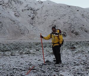 Duncan posing with track marker in front of the snow covered slopes