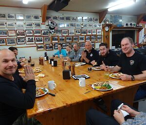 A happy group of people sitting around the table eating indian food