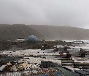 High seas cause waves to come over the isthmus on Maqcquarie Island. Station buildings are seen in the background, the beach is in the foreground.