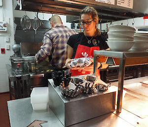 Mess kitchen complete with fish and chip shop signage and two expeditioners working behind counter