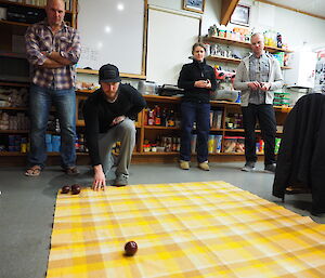 Ben bowling a carpet bowl on an orange blanket