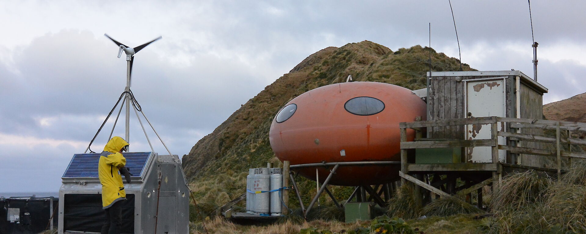 Louise standing in front of the power generator at Brothers Point hut