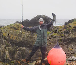 Ben standing on sea shore holding up a large fishing marker buoy