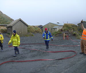 Expeditioners aroiund a fire hose on the ground