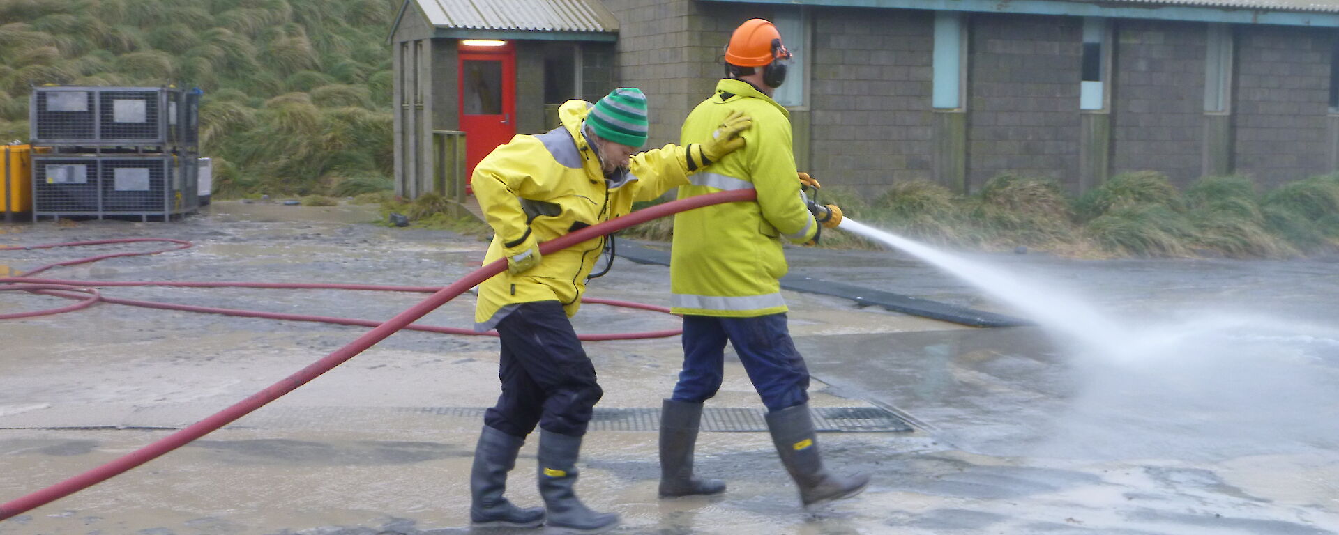 Marion and Nick using a fire hose and spraying water