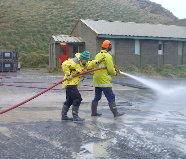 Marion and Nick using a fire hose and spraying water