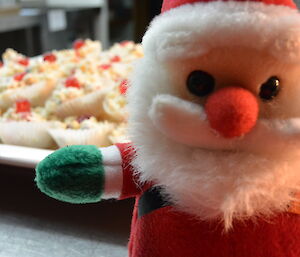 A toy santa and a plate of white christmas sweets