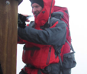 Male expeditioner concentrates while opening a hut door.
