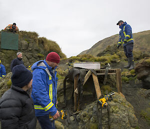 Expeditioners standing around a giant prop toilet seat built into the hill