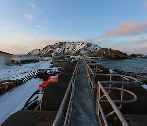 Snow covered hill in rear and walkway atop fuel tanks in the foreground