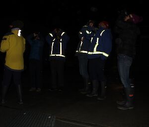 People looking at the sky in the dark with binoculars