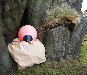 A bulker bag and marine buoy stacked beside a rock ledge