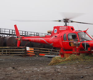 Red heli on pad at machinery shed