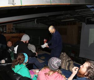 Expeditioners in the green store on the mezzanine on couches ready to watch a film.