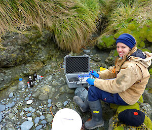 Helena sitting on rocky beach with pH probe