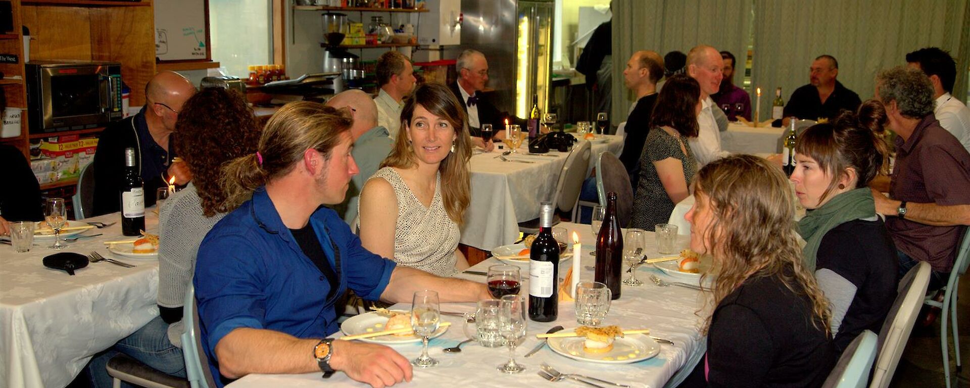 The mess hall filled with tables and expeditioners sitting down to a nice dinner