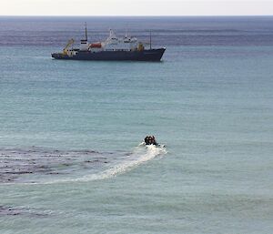 Small inflatable boat driving towards ship