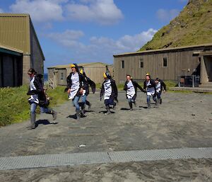 Expeditioners dressed in penguin suits running in a line