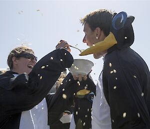 Expeditioner feeding another expeditioner in penguin suits