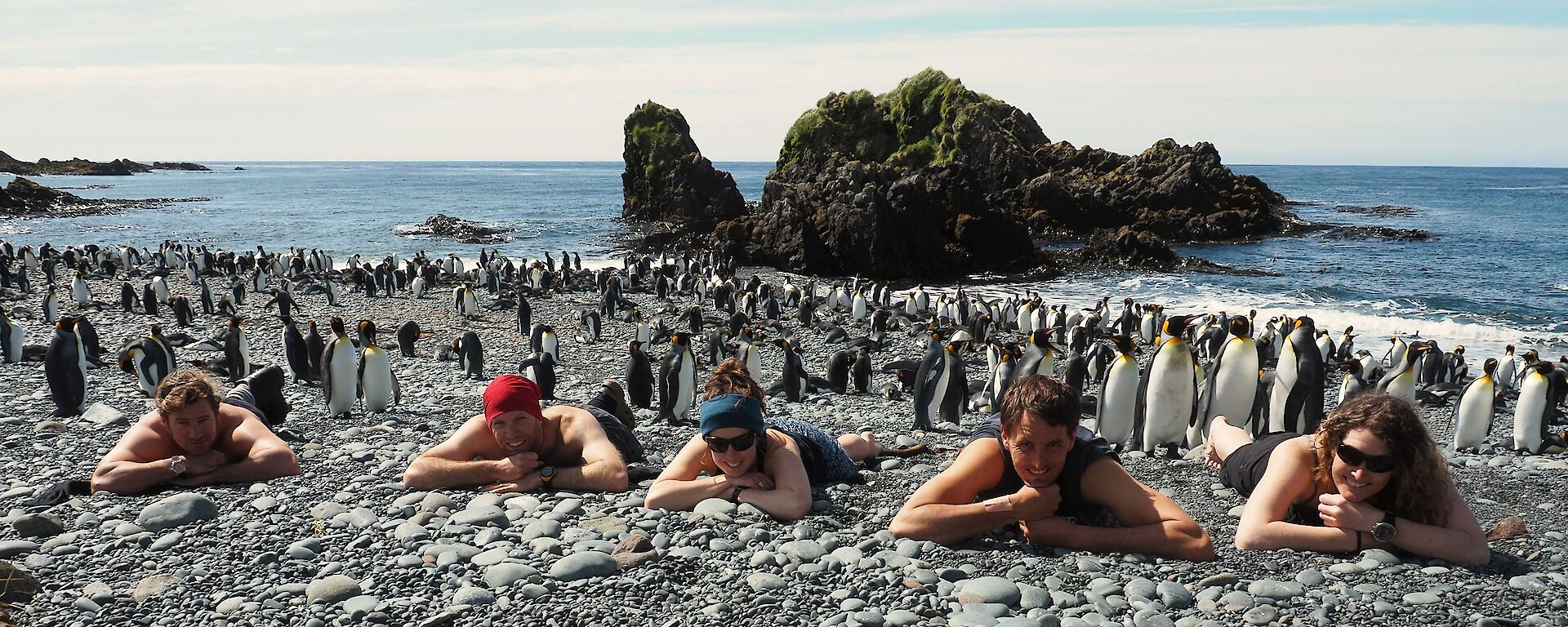 Expeditioners lying on the beach with penguins in the background