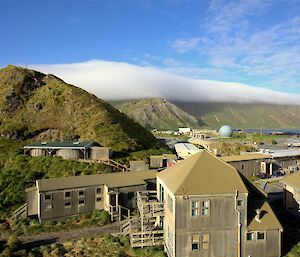 Sun shining on station buildings and cloud over plateau in distance