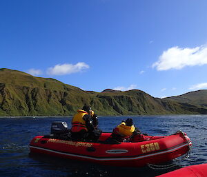 Three people in a red inflatable rubber boat