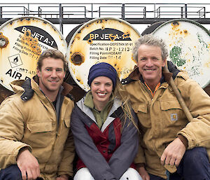 Summer Remediation Team: Robbie, Helena, and Terry sit in front of barrels and smile broadly.