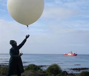 One of the BoM team releasing their hydrogen balloon on a rare windless day — L'Astrolabe on the water in background