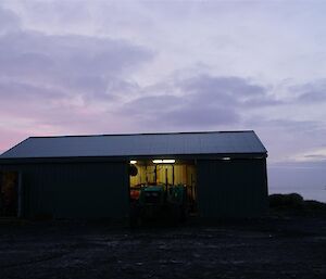 A pink sunrise sky over the boat shed with L'Astrolabe in the background