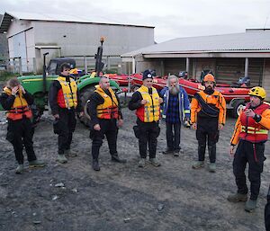 Watercraft operators, all dry-suited up, being briefed outside the boatshed before commencing operations for the day