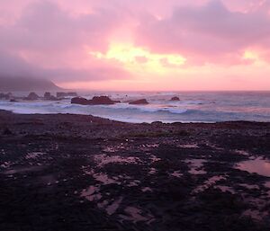 A pink sunset over the beach and rocks of Hasselborough Bay