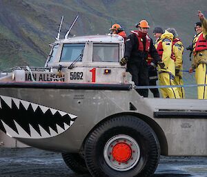 Plumber Tim waves goodbye from the deck of a big tin boat with wheels called a LARC