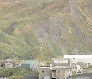 Four figures with packs on are small in the vista of station and the plateau in background