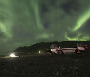 Aurora above a parked LARC vehicle, with the green beam of the LIDAR clearly visible through the middle