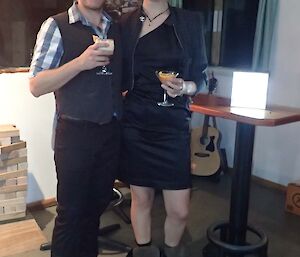 A couple stand with drinks in their hand smiling broadly.