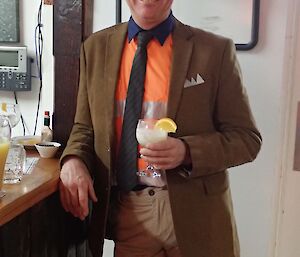 A man stands at the bar in a high-vis shirt completed with suit jacket and tie