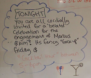 An invitation to drinks to celebrate the engagement written on a whiteboard