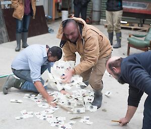 Two masked men are trying to get all the money off the floor