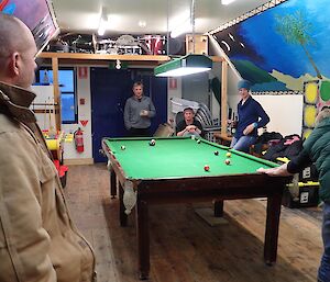 A man gets ready to play a shot at pool while others watch
