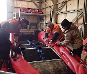 Four men working to replace the floor of the boat
