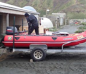 A man on the back of the boat starting the engine to warm it up