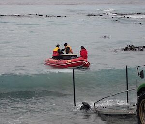 Boat is on the water with its crew after having been launched off the back of a trailer being pulled by a tractor.