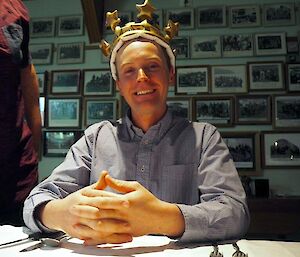 A man smiles at the camera wearing a blow-up crown