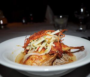 A plate of food — quail on noodles with asian salad on top