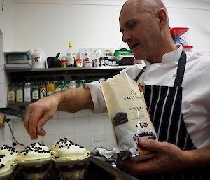 The chef putting the final garnish on glasses of trifle